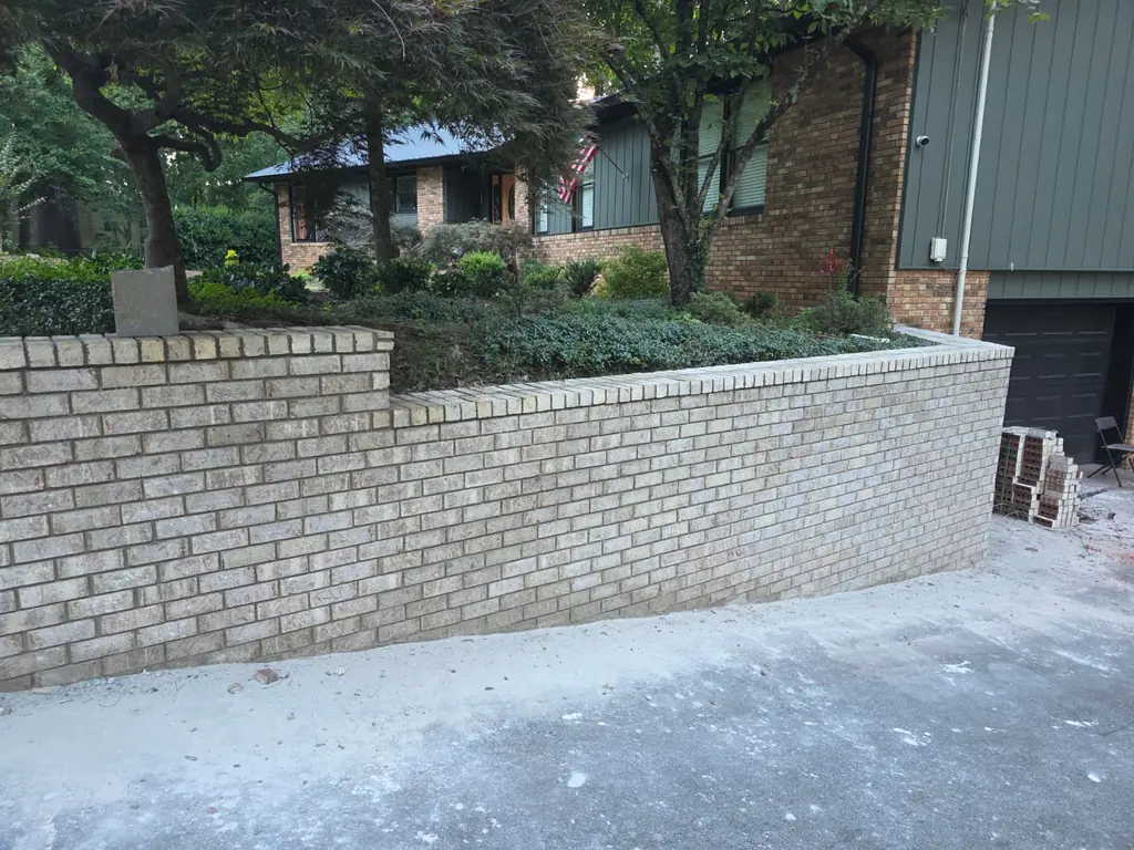 Completed tan brick retaining wall with capped soldier course