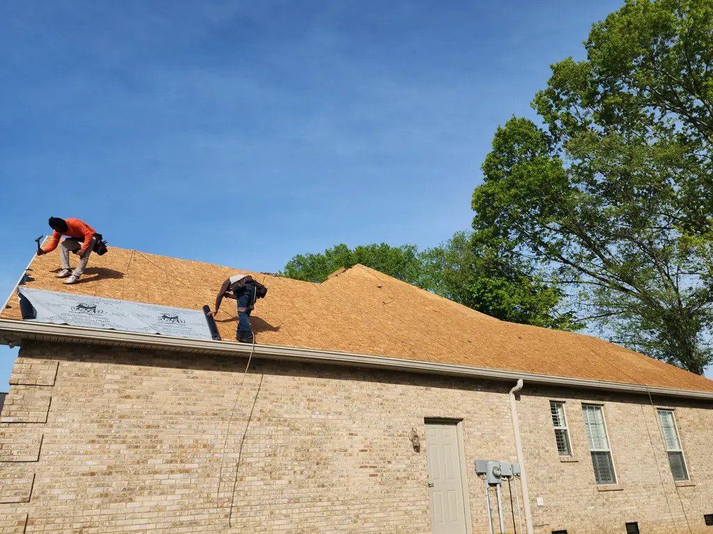 Legacy Construction crew installing roof decking on a brick home